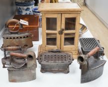 Four French coal/slug irons, three trivets and a stripped pine glazed cabinet, 37cm high