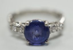 A modern Illiana platinum, single stone round cut tanzanite and four stone diamond set dress ring,