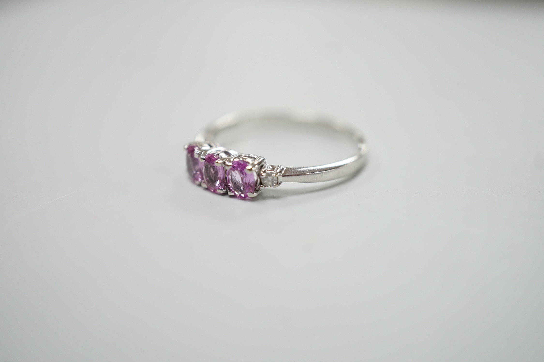 A modern 14ct white gold, three stone pink sapphire and two stone diamond chip set ring, size L, - Image 2 of 4