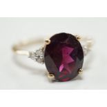 A modern 9ct gold, single stone oval cut garnet and six stone diamond chip set dress ring, size R/S,