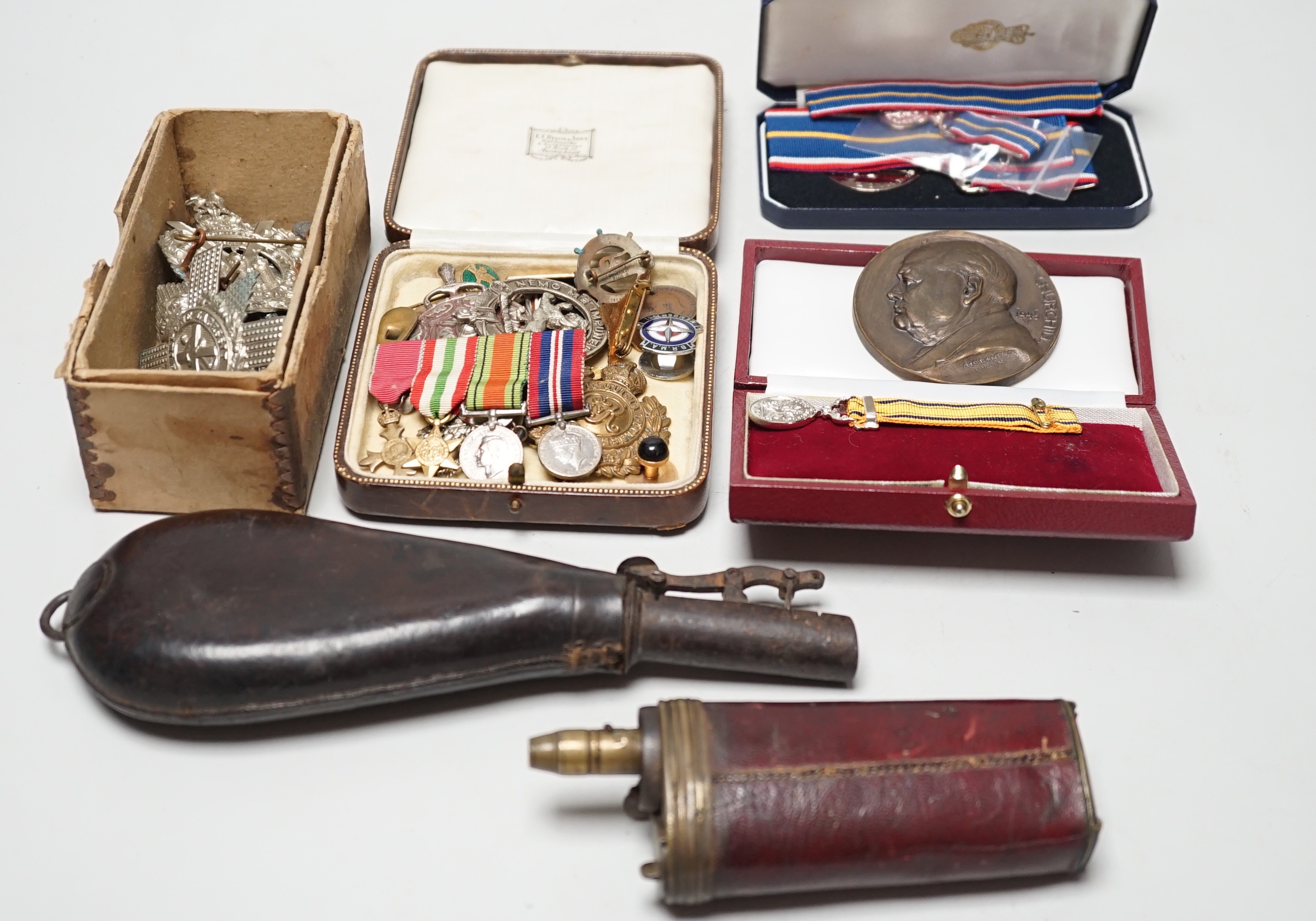 Two powder flasks and militaria including cap badges and miniature medals