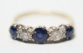 A modern 18ct gold, three stone sapphire and two stone diamond set half hoop ring, size R, gross
