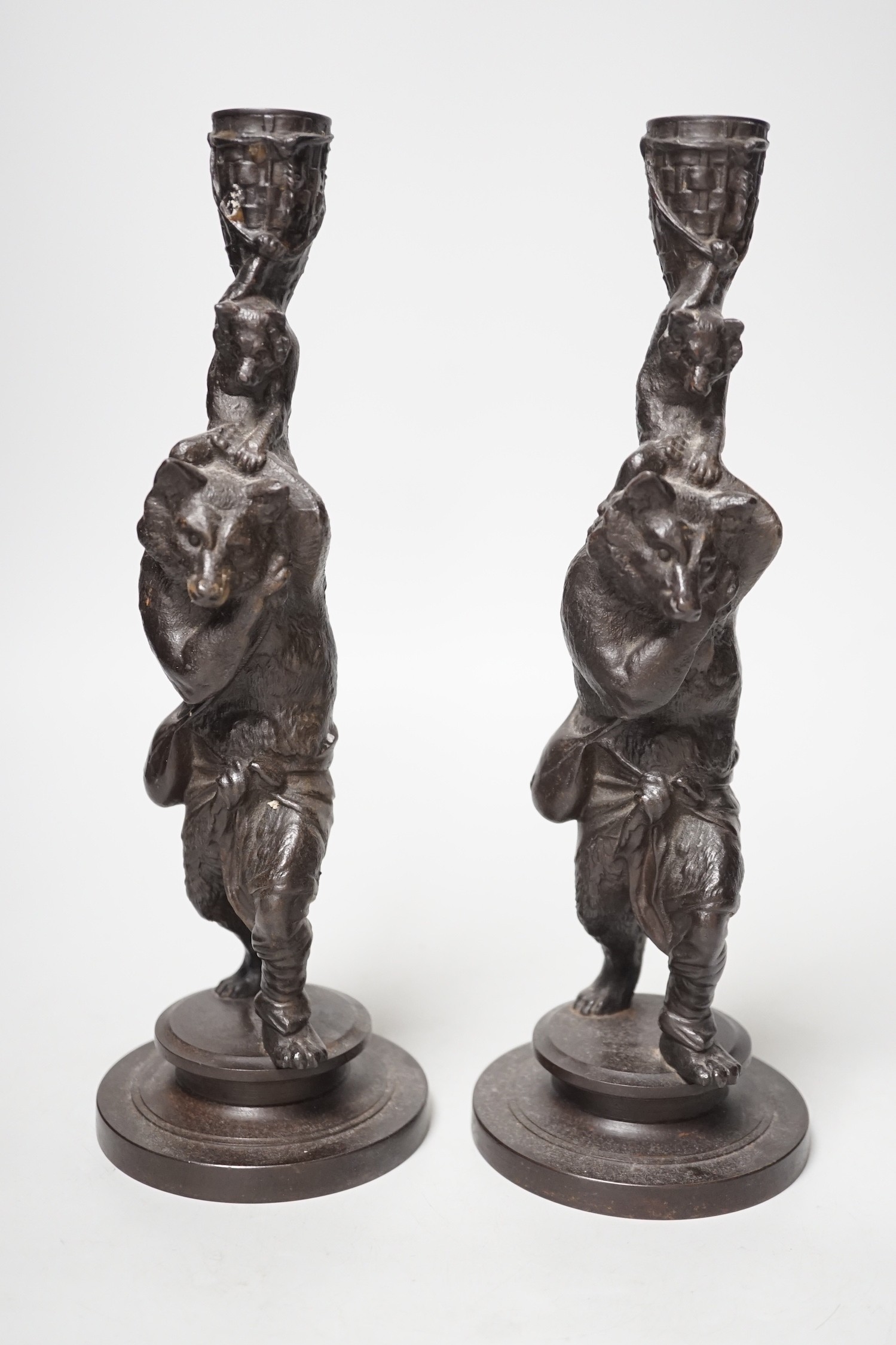 A pair of cast iron candlesticks in the form of anthropomorphised foxes and cubs. 27cm tall