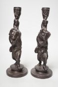 A pair of cast iron candlesticks in the form of anthropomorphised foxes and cubs. 27cm tall