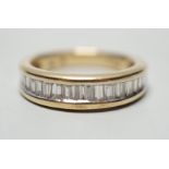A modern 14k yellow metal and graduated baguette and trapeze cut diamond set half eternity ring,