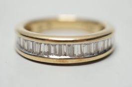 A modern 14k yellow metal and graduated baguette and trapeze cut diamond set half eternity ring,