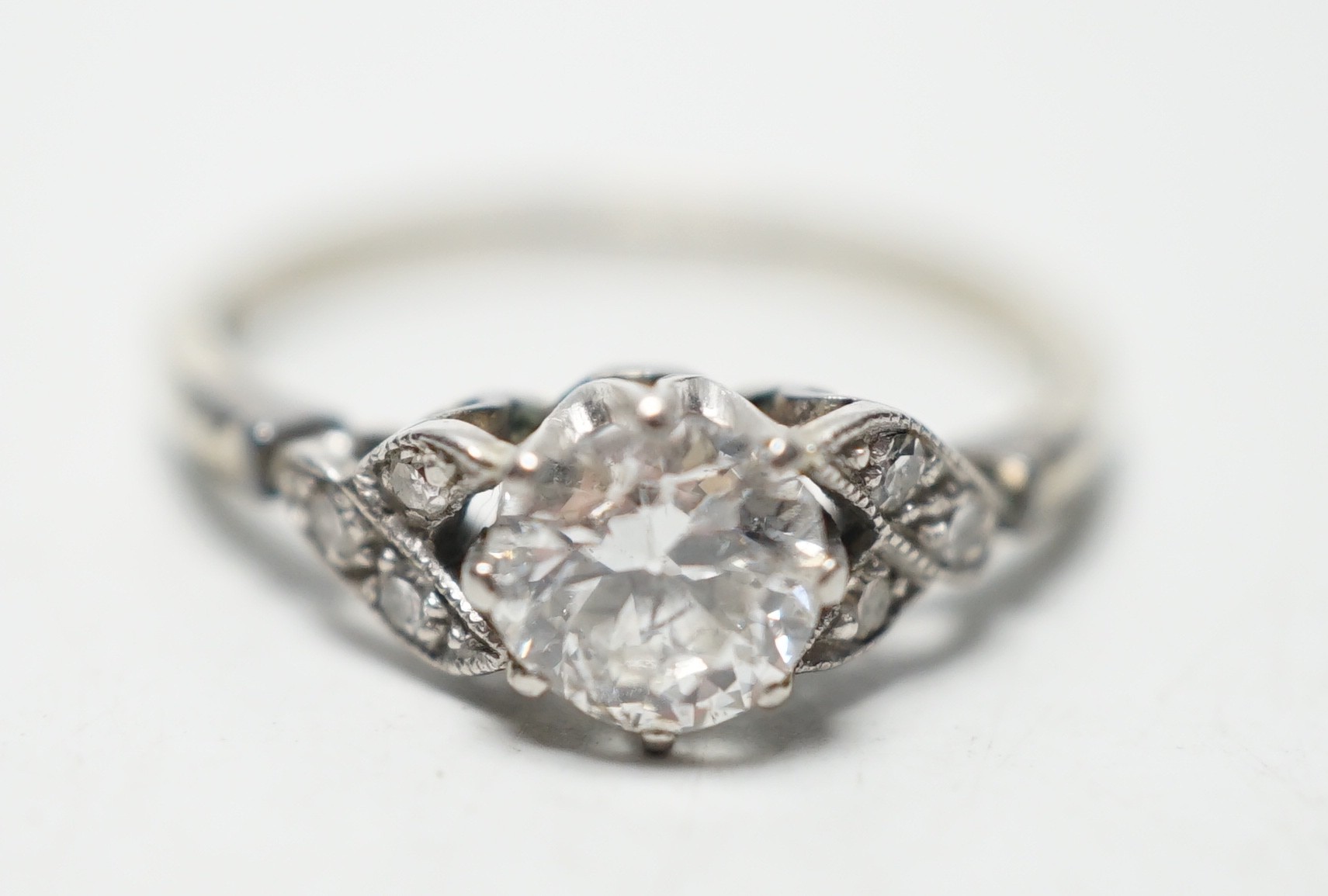 An 18ct white metal and single stone diamond ring, with diamond chip set shoulders, the stone