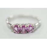 A modern 14ct white gold, three stone pink sapphire and two stone diamond chip set ring, size L,