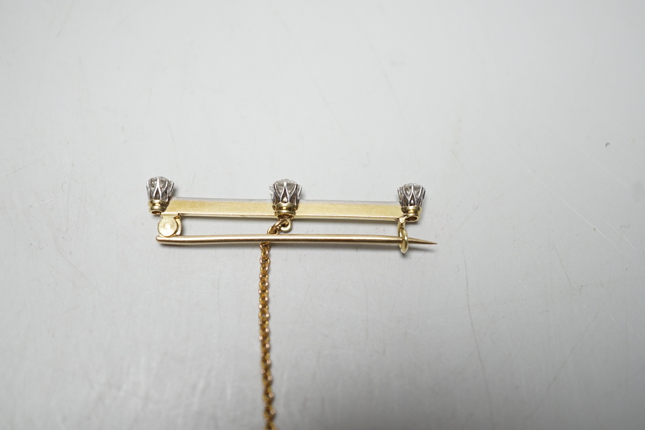 A yellow metal and three stone diamond set bar brooch, 36mm, gross weight 2.8 grams. - Image 4 of 5