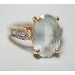 A modern 18ct gold and oval cut aquamarine set dress ring, with diamond chip set shoulders, size