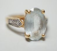 A modern 18ct gold and oval cut aquamarine set dress ring, with diamond chip set shoulders, size