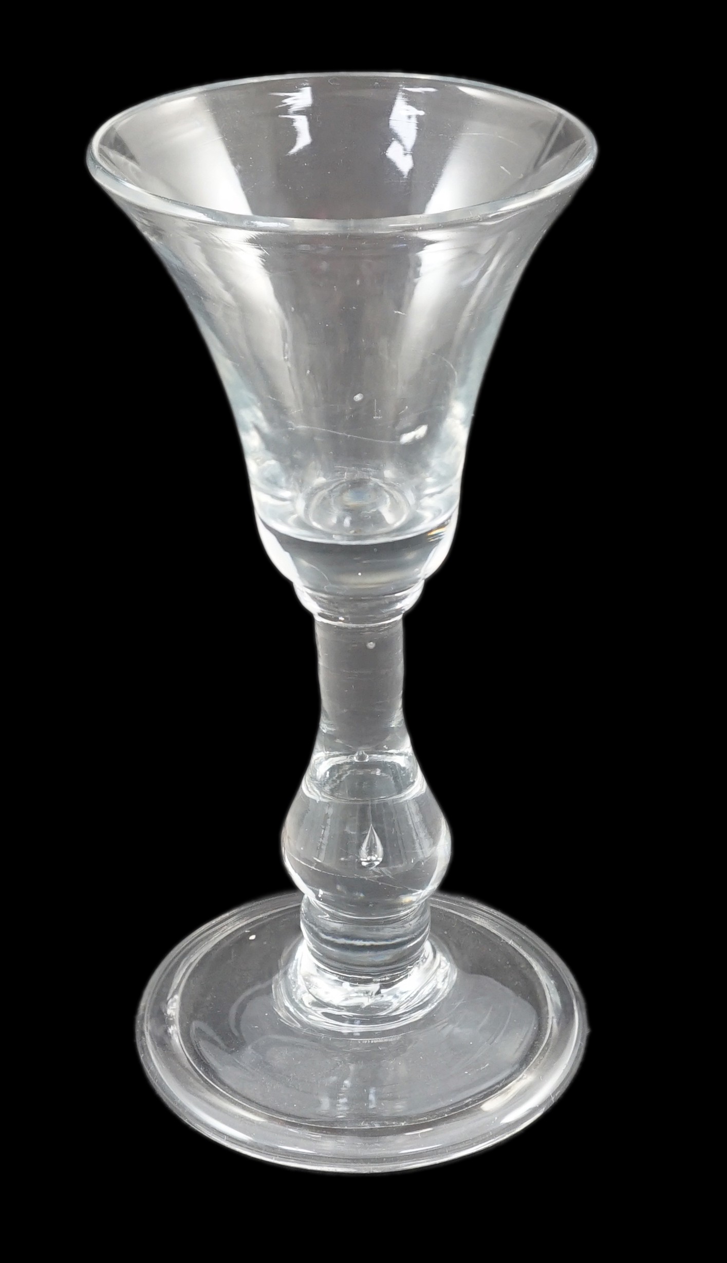 A true baluster wine or cordial glass, c.1720, the bell-shaped bowl above a tear drop baluster stem,