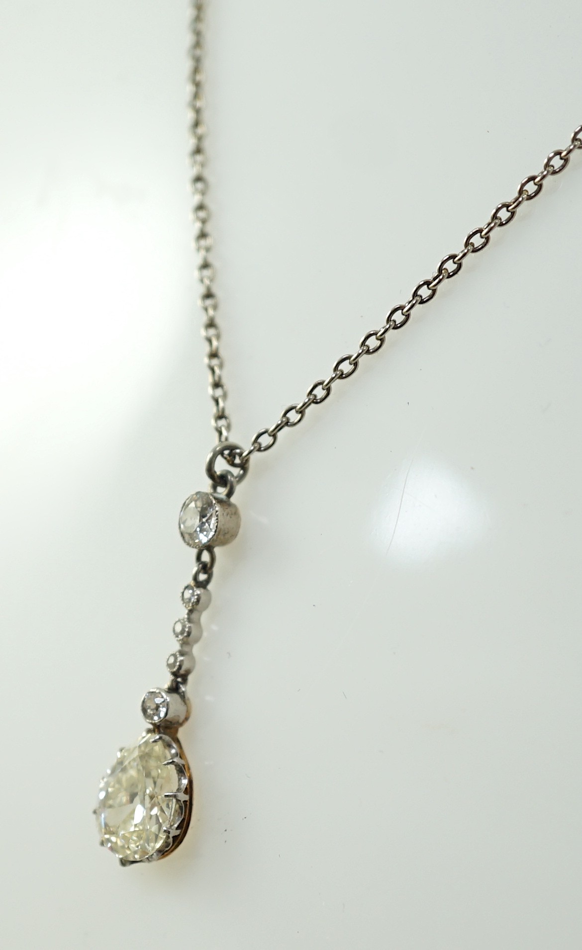 An early to mid 20th century white and yellow gold, six stone diamond set drop pendant, on a white - Image 3 of 5