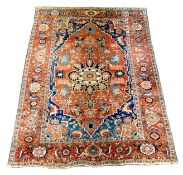 An antique Heriz brick red ground carpet, with large central floral medallion within a wide