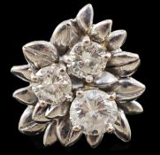 An 18ct white gold and three stone diamond set flowerhead ring, the largest stone weighing