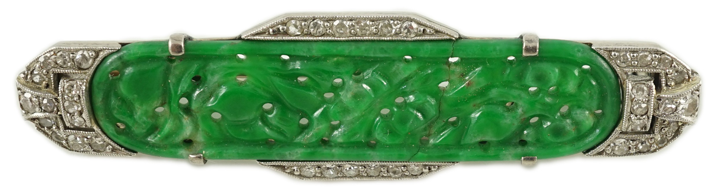 An Art Deco white gold, jadeite and diamond set bar brooch, the jadeite with carved foliate