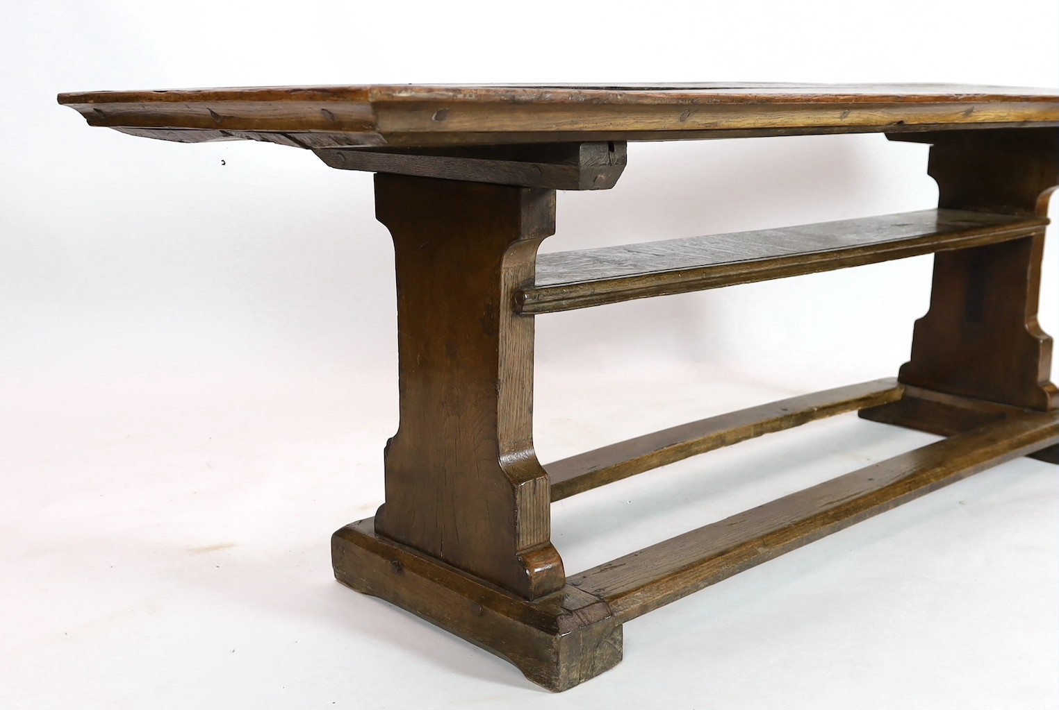 A narrow oak refectory table, part 17th century, the cleated twin plank top above trestle supports - Image 4 of 4