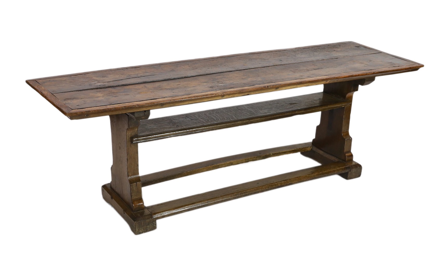 A narrow oak refectory table, part 17th century, the cleated twin plank top above trestle supports