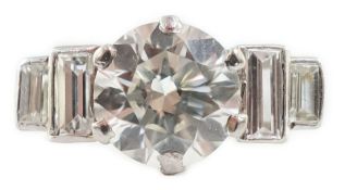 A platinum and single stone diamond ring, with graduated baguette cut diamond set shoulders, the