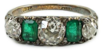 An early 20th century 18ct gold, three stone diamond and two stone emerald set half hoop ring,