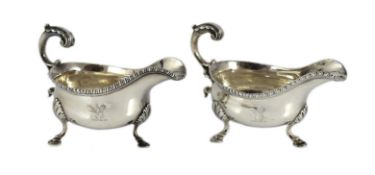 A near pair of George III silver sauceboats, with gadrooned borders, engraved crest and flying