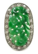 A 1920's/1930's white gold, jadeite and diamond set oval dress ring, the foliate carved jadeite,