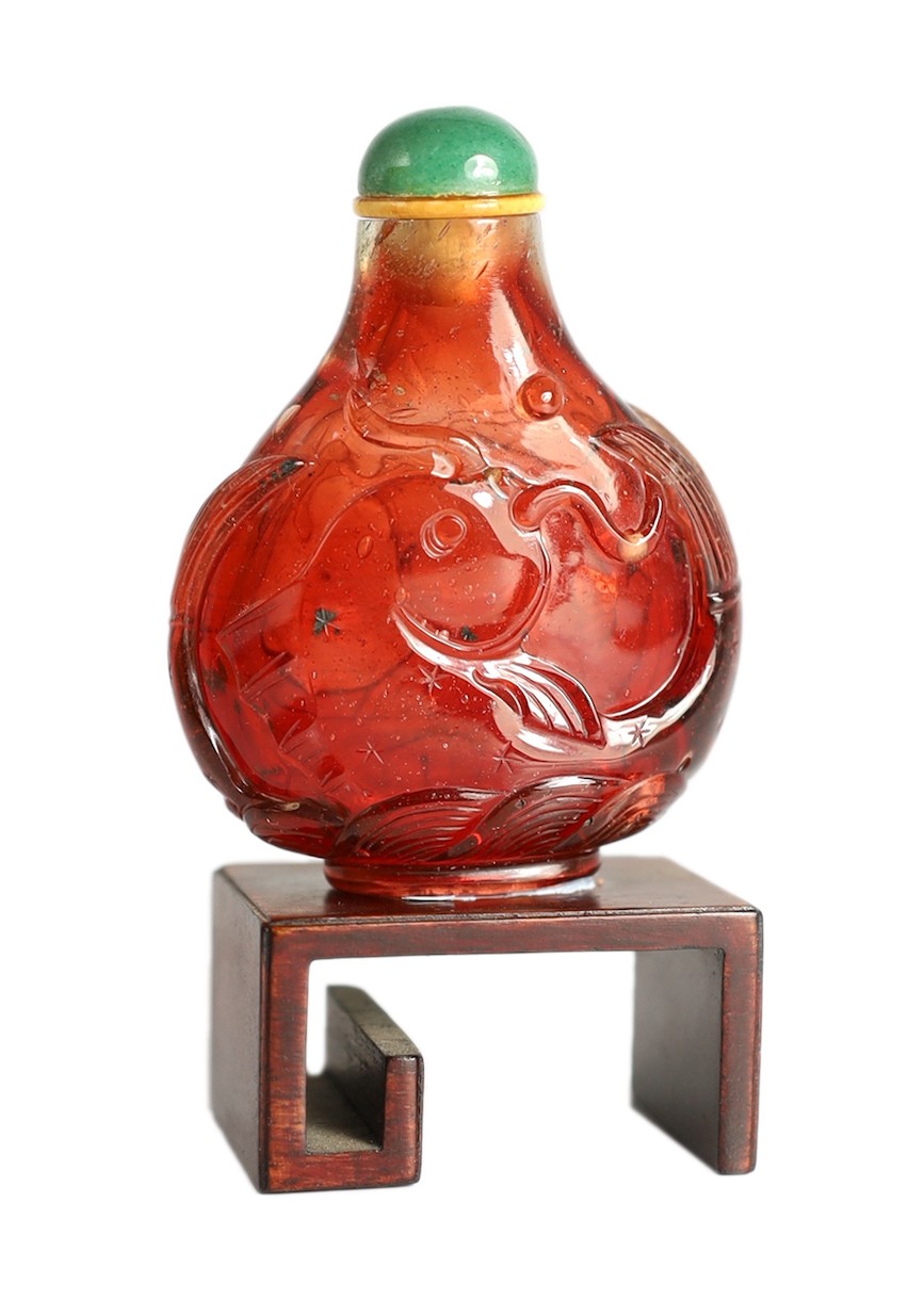 A Chinese ruby red glass ‘leaping carp’ snuff bottle, 1750-1850, each side carved in high relief