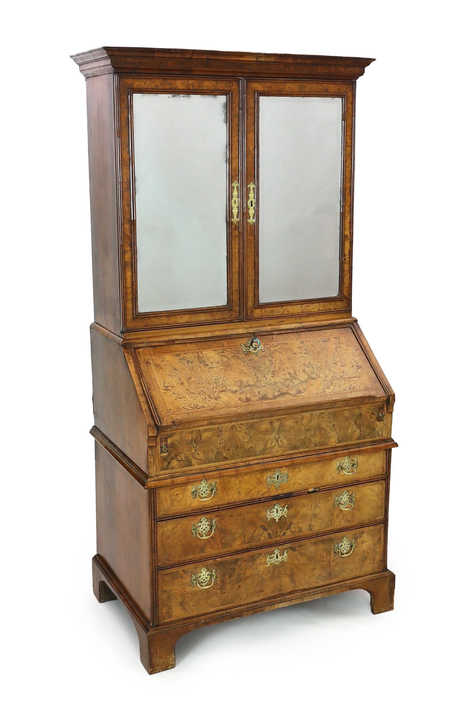 A George I walnut bureau bookcase, with moulded cornice and two bevelled mirrored doors enclosing