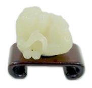 A Chinese white jade figure of a pug dog, 19th/20th century, the dog biting a sprig of lingzhi
