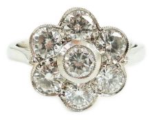 A platinum and seven stone diamond cluster set flower head ring, the millegrain set stones with an