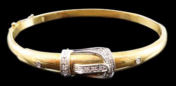 A gold and diamond set hinged bangle with central buckle motif, interior diameter 58mm, gross weight