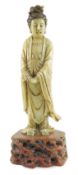 A Chinese soapstone standing figure of Guanyin, 19th century, of creamy pale green stone, her