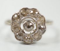 A 1920's white metal and ten stone millegrain set diamond flower head cluster ring, size P/Q,