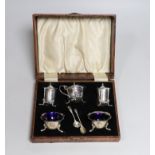 A cased 1930's silver five piece condiment set, with two associated silver spoons.