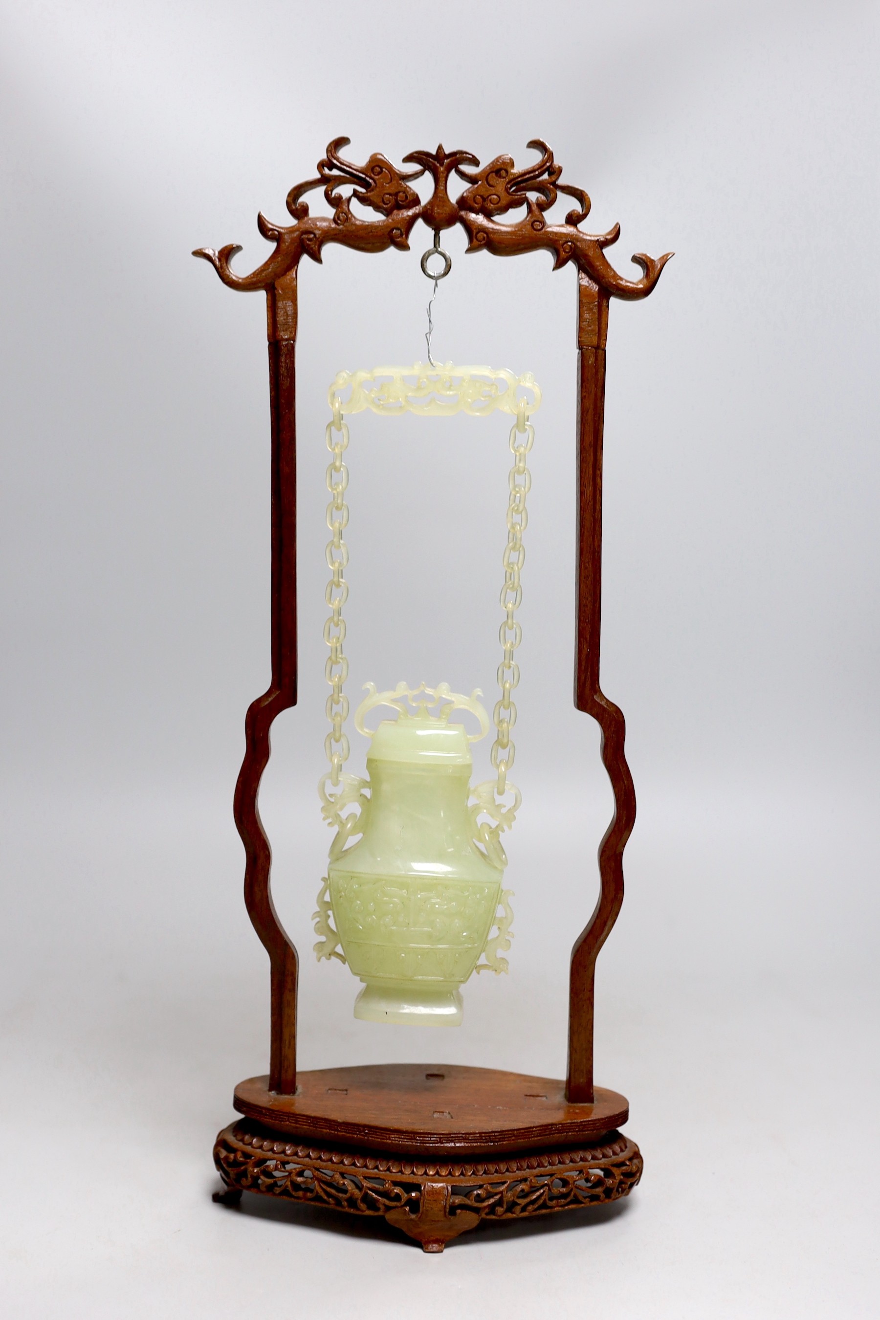 A Chinese bowenite jade hanging vase and cover together with a carved hard wood stand, one foot