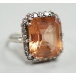A white metal and emerald cut orange/peach topaz set dress ring, with diamond set border, size I/J,