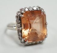 A white metal and emerald cut orange/peach topaz set dress ring, with diamond set border, size I/J,