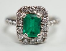 A modern 750 white metal, emerald and diamond set octagonal cluster ring, with diamond set