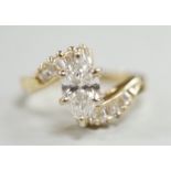 A yellow metal and singe stone marquise cut diamond set crossover dress ring, with baguette cut