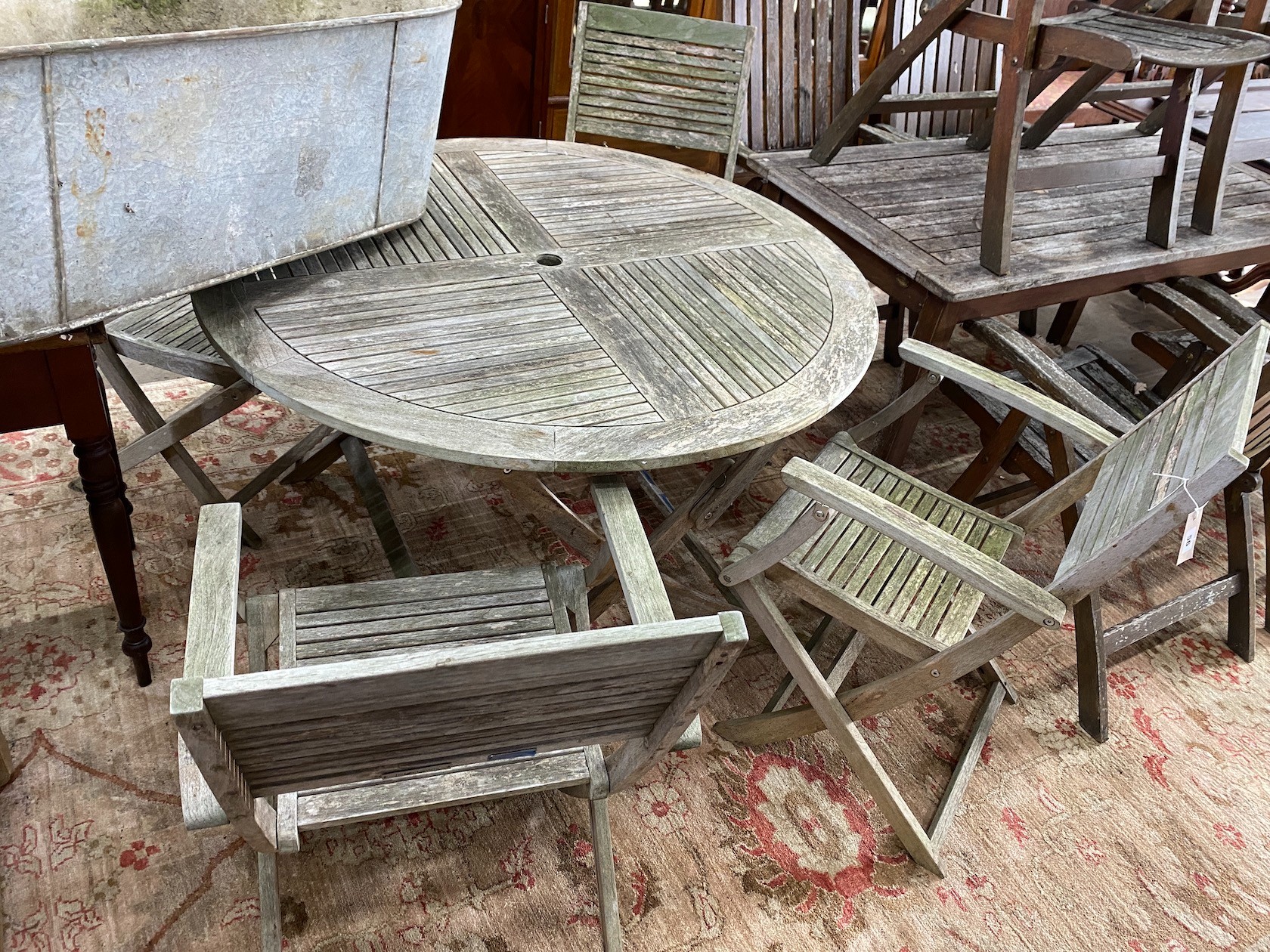 A John Lewis retailed weathered teak circular folding garden table, diameter 120cm, height 74cm