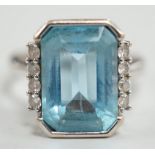 A 750 white metal and emerald cut blue topaz set dress ring, with diamond chip set borders, size