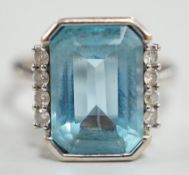 A 750 white metal and emerald cut blue topaz set dress ring, with diamond chip set borders, size