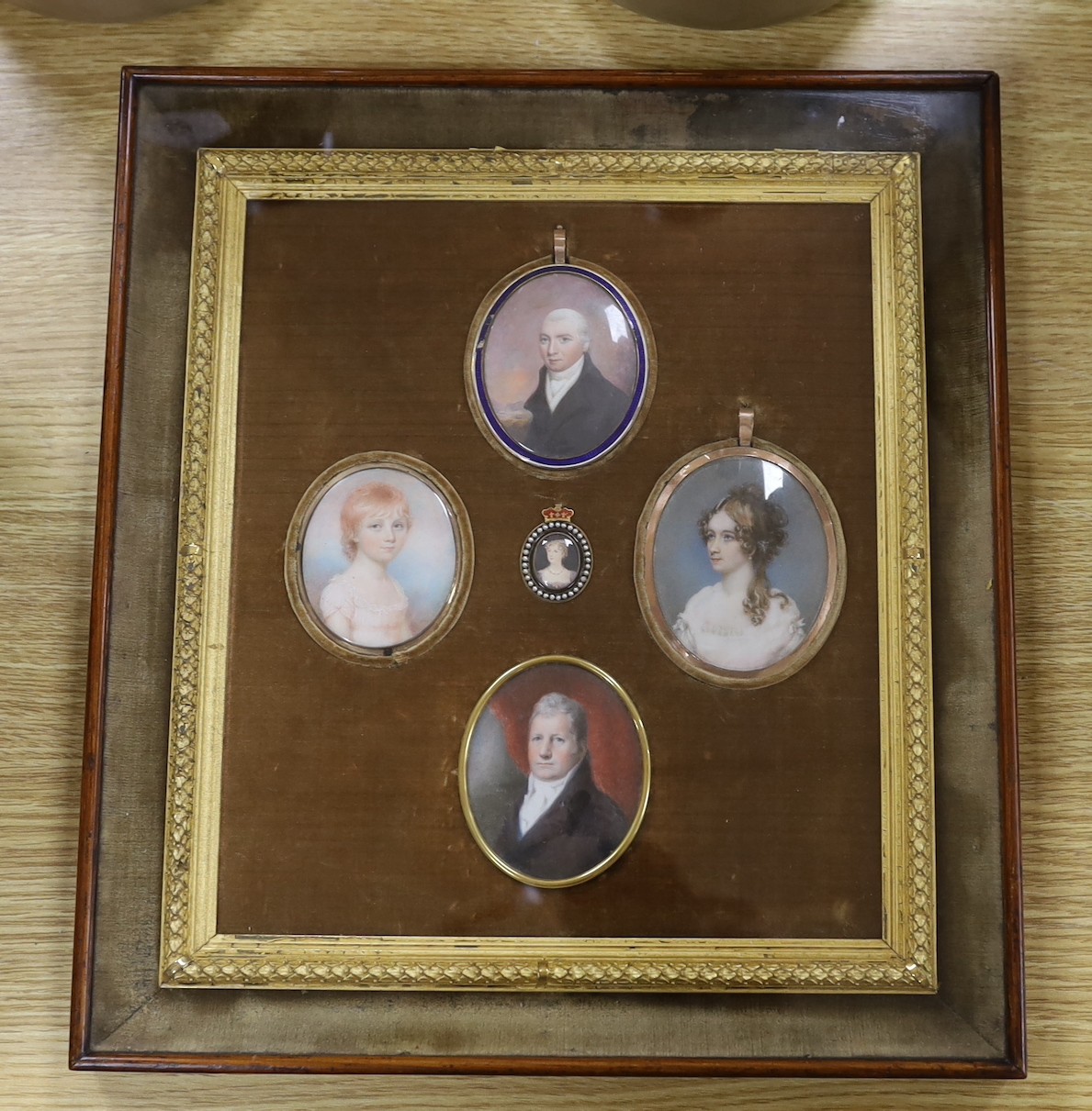 A group of five 19th century portrait miniatures on ivory, framed as one, in a decorative gilt and