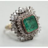 A white metal and single stone emerald set dress ring, bordered with two stepped bands of round