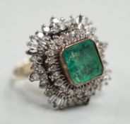 A white metal and single stone emerald set dress ring, bordered with two stepped bands of round