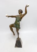 A French Art Deco patinated bronzed spelter dancer, holding two ivory spheres, on marble base,