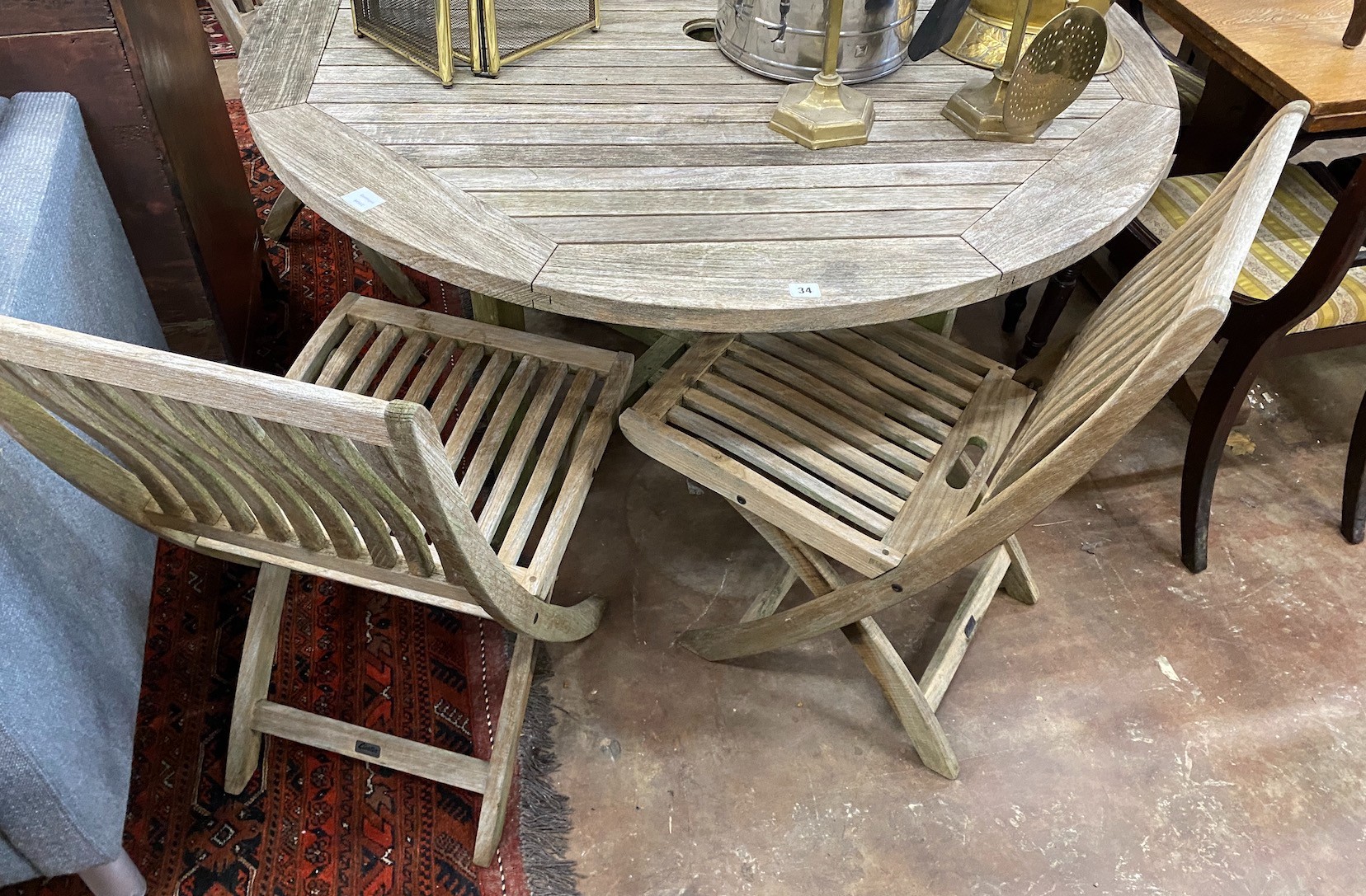 A Gloster weathered teak circular garden table, diameter 130cm, height 70cm and four folding chairs