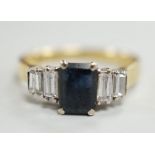 A modern 18ct gold and single stone emerald cut sapphire set ring, with graduated baguette cut