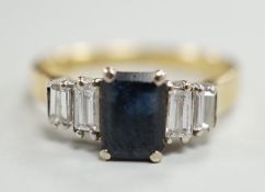 A modern 18ct gold and single stone emerald cut sapphire set ring, with graduated baguette cut