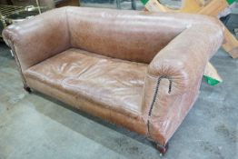 An early 20th century tan leather drop arm Chesterfield settee, width 160cms, depth 84cms, height